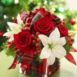 Red roses and white lilies in a plaid-wrapped square vase