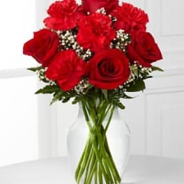 Red roses and carnations in a clear glass vase