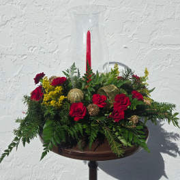 Red carnations and yellow filler in a glass hurricane vase with a red candle
