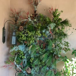 Large wall arrangement of pine, berries, and pinecones with a lantern