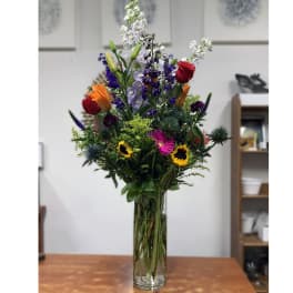Tall mixed bouquet in a clear glass vase with colorful blooms