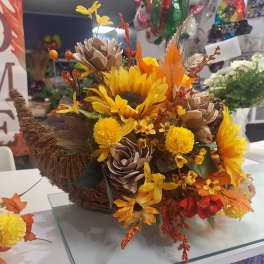 Autumn floral arrangement with sunflowers and pinecone accents in a woven basket