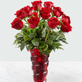 Red roses arranged in a tall red glass vase