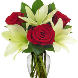 Red roses and white lilies arranged in a clear glass vase
