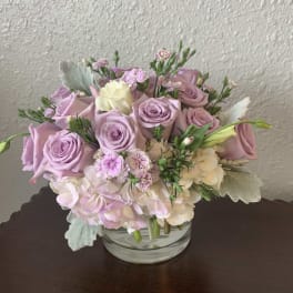 Lavender roses and pale hydrangeas in a clear glass vase