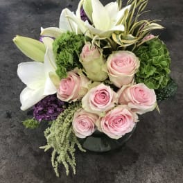 Pink roses and white lilies arranged in a low glass vase