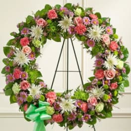 Large floral wreath with pink and white flowers on a black stand