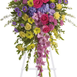 Standing floral spray with pink roses, purple orchids, and yellow blooms on an easel