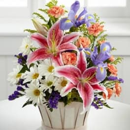 Mixed bouquet with pink lilies, purple irises, and white daisies in a basket