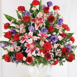 Large mixed bouquet of red, pink, and purple flowers in a white vase