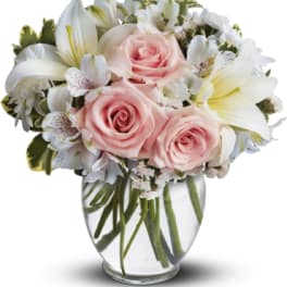 Pink roses and white lilies arranged in a clear glass vase