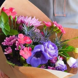 Bouquet of pink and purple flowers wrapped in brown paper