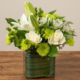 White lilies and roses in a green glass vase