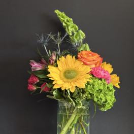 Mixed bouquet with a sunflower, roses, hydrangea, and alstroemeria in a glass vase