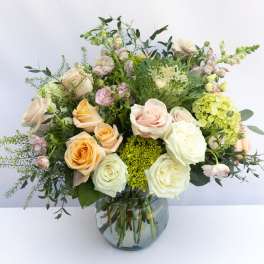 Mixed pastel roses and greenery in a glass vase