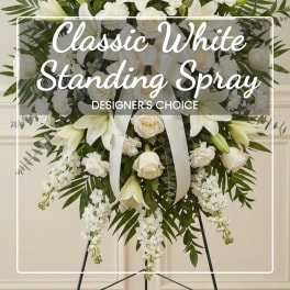 White standing spray with lilies, roses, and ribbon on an easel