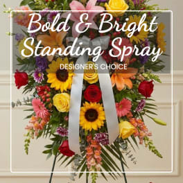 Standing spray with mixed bright flowers and a silver ribbon bow