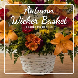 Autumn flower basket in a white wicker container with orange, red, and yellow blooms