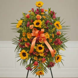 Standing floral spray with sunflowers, orange roses, and a ribbon bow
