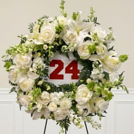 White floral wreath on an easel with a red 24 sign in the center