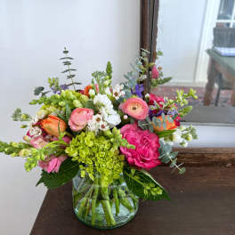 Mixed bouquet of pink, white, orange, and green flowers in a glass vase