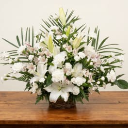 White lilies and carnations arranged in a wicker basket