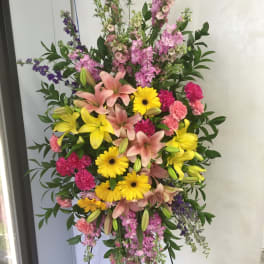 Tall standing floral spray with pink lilies, yellow gerberas, and mixed blooms