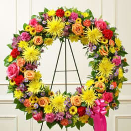 Colorful floral wreath on a black easel with a pink ribbon