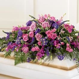 Large arrangement of pink and purple roses on a white casket