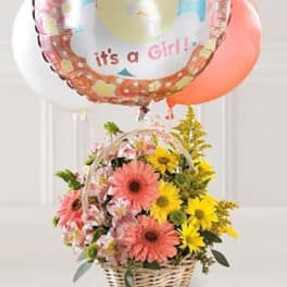 Basket of pink and yellow flowers with baby girl balloons