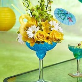 Yellow and white flower arrangement in a blue goblet vase