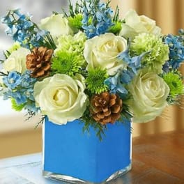 White roses and blue flowers arranged in a blue square vase