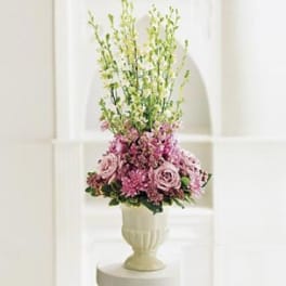 Pink and lavender floral arrangement in a white urn vase