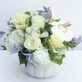 White and lavender floral arrangement in a white pumpkin-shaped container