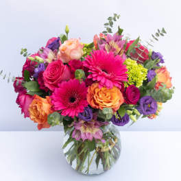 Mixed bouquet of pink, orange, and purple flowers in a glass vase