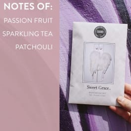 Hand holding a scented sachet package beside a pink note card