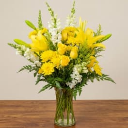 Yellow lilies and white snapdragons in a clear glass vase