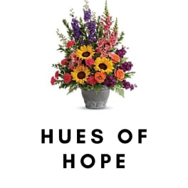 Colorful mixed flower arrangement in a gray pot with "HUES OF HOPE" text below