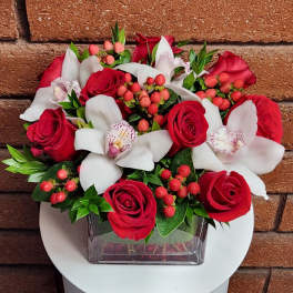 Red roses and white orchids in a square glass vase