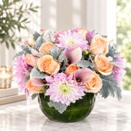 Peach roses and pink dahlias in a green glass bowl