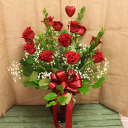 Red roses in a glass vase with a red ribbon and heart pick