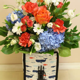 Mixed bouquet of roses, carnations, hydrangeas, and daisies in a patterned lunch bag