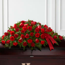 Red rose and carnation casket spray with a red ribbon