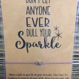 Card with the words "Don't let anyone ever dull your sparkle" and a purple bracelet