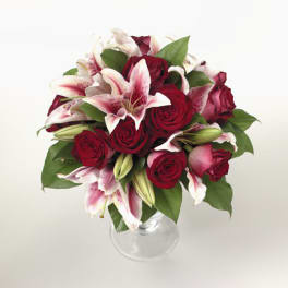 Bouquet of red roses and pink lilies in a clear glass vase
