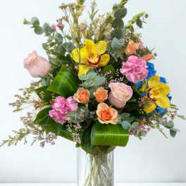 Mixed bouquet of roses, orchids, and carnations in a glass vase