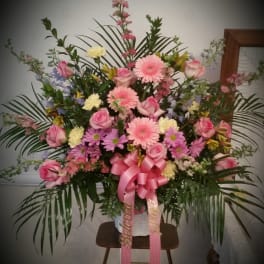 Large pink and purple floral standing arrangement with a ribbon bow