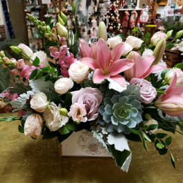 Pink lilies and pale roses arranged in a decorative box