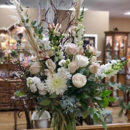 Tall bouquet of white and blush flowers in a clear glass vase