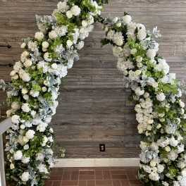 Large white floral arch with roses and hydrangeas